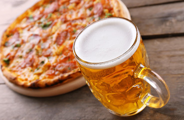 Tasty pizza and glass of beer are on wooden table, close up