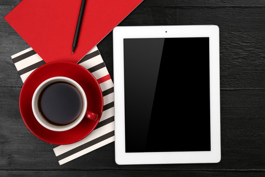 Digital tablet with cup of coffee and notebook on wooden table, closeup