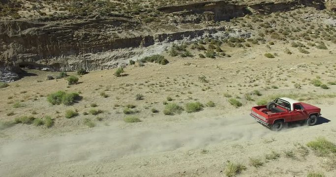 Aerial scene of car traveling on dirt road a dry, rocky, landscape. Monumental scenery. Scene starts form the side of the car ends on the front. Canyon of Piedra Parada, Chubut, Patagonia Argentina.