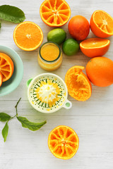 Juicy slices of oranges and juicer on white wooden table