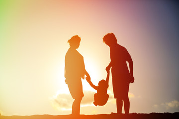 Fototapeta premium happy family including pregnant mother, father and toddler at sunset