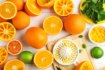 Cutting and juicing delicious oranges on white wooden table
