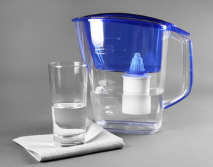 Filter and glass of water with napkin on grey background