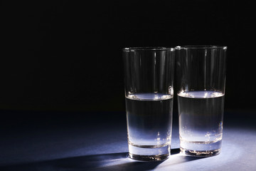 Two glasses of pure water on dark background