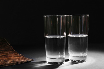 Two glasses of pure water on dark background
