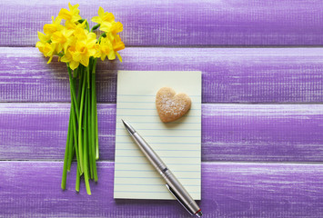 Yellow daffodils and notebook on wooden background