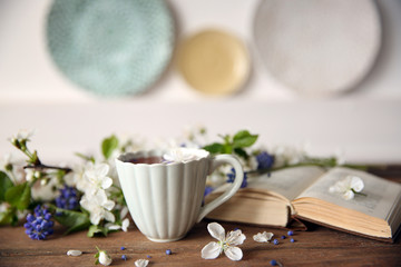 Open book and cup of tea  on wooden table