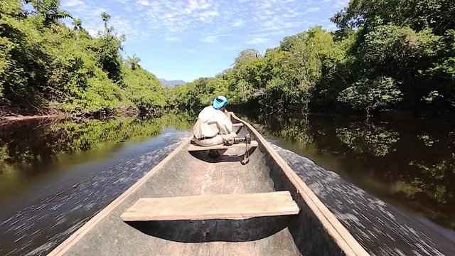 Male explorer sailing on indigenous canoe in the Amazon jungle