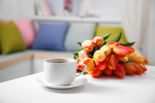 Tulips and cup of tea on white table
