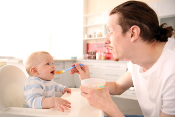 Obraz na płótnie Canvas Father feeding his baby son