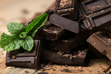Chocolate pieces with mint leaves on wooden background