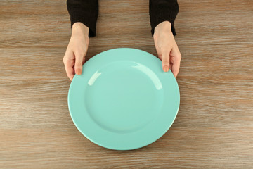 Woman hands holding empty plate, top view