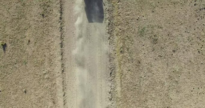 Aerial top scene of off road car in a dirt road on a desertic, dry, rocky, sand landscape. Camera follows the automobile. Piedra parada, chubut, Patagonia, Argentina.
