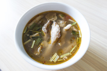 Super chicken foot soup in white bowl on wooden table.
