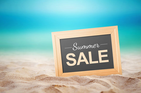 Summer sale Concept. Close up wooden picture frame and summer sale text on the beach