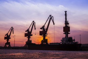 Fototapeta premium In the evening, the silhouette of port cranes