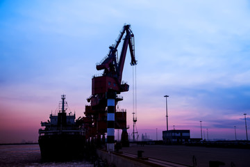Fototapeta na wymiar In the evening, the silhouette of port cranes