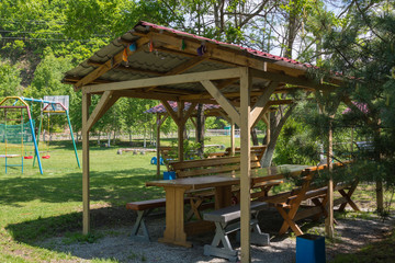 Resting place under a canopy outdoors. A table and benches.