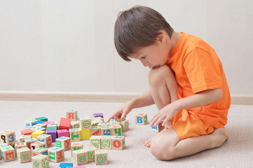 Child playing with toy cubes in the room