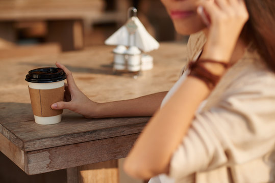Cropped image of woman drinking take-out coffee and talking on phone