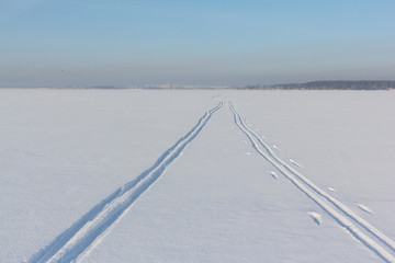 Two ski tracks leaving afar on a snow field in winter day