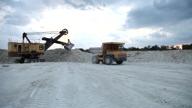 excavator loads a truck rock in the quarry
