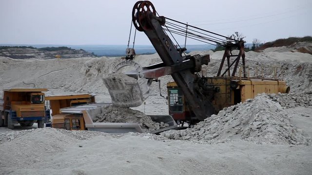excavator loads a truck rock in the quarry
