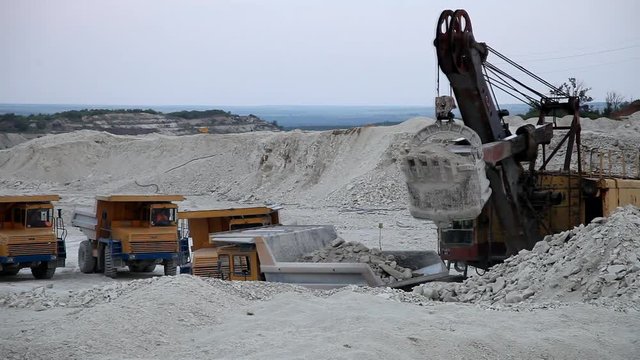 excavator loads a truck rock in the quarry
