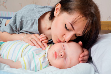 Obraz na płótnie Canvas Portrait of beautiful mother with her 7 months old baby sleeping