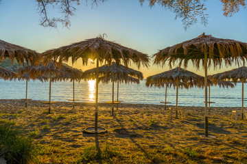 Fototapeta na wymiar Magnificent sunset through umbrellas at the beach. Summer day in