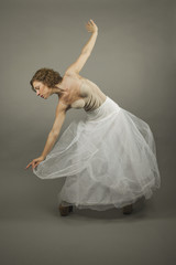 Young expressive ballerina with a white long tutu practicing bal