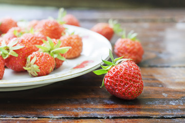 Fresh ripe strawberry is scattered on a white plate.