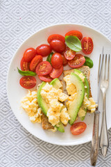 Scrambled eggs and avocado on whole grain toast. Concept of healthy breakfast.
