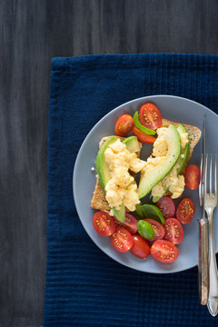 Scrambled eggs and avocado on whole grain toast. Concept of healthy breakfast.