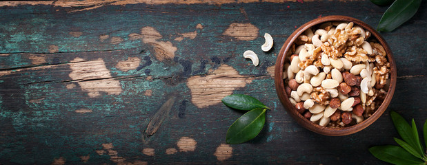 Nuts in vintage spoons on a vintage dark background, horizontal with copy space, top view