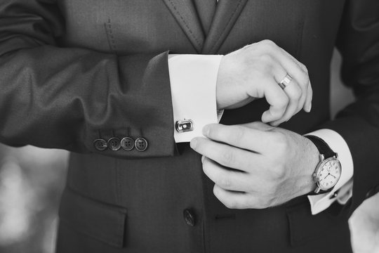 Black and white image of man in suit. Mail dress fashion. Close up of man hands and sleeves of blue suit and white shirt. Groom, businessman or groomsman.