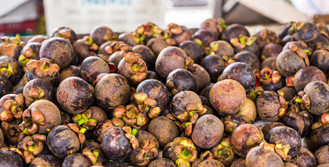 Fresh mangosteen for sale at an outdoor market.