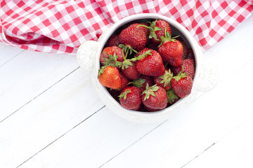 Top view of a bowl with strawberry on wooden background