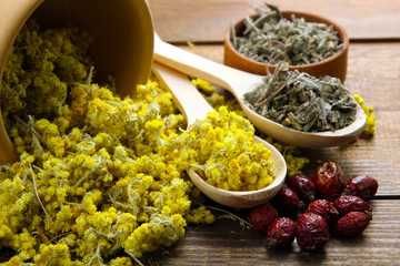 immortelle dried flowers in wooden mortar on wooden brown background with berries