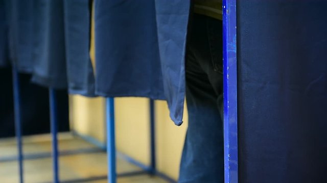 Unrecognizable people casting their votes inside voting booths during elections