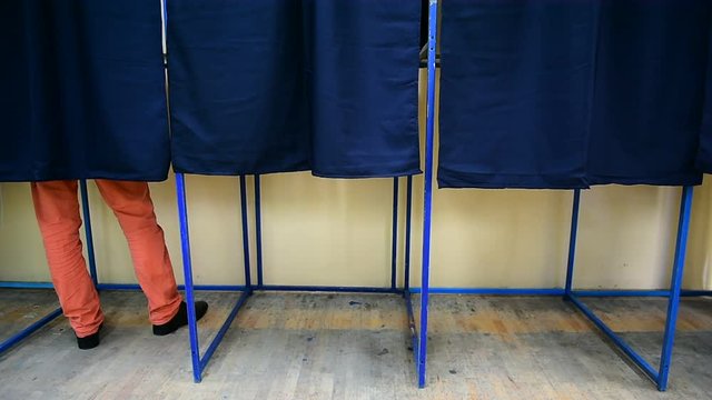 Unrecognizable people casting their votes inside voting booths during elections