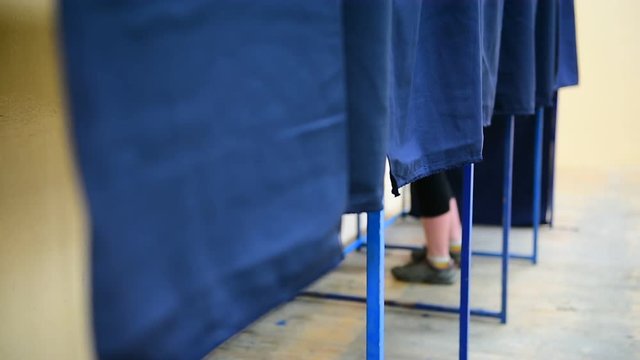 Unrecognizable people casting their votes inside voting booths during elections