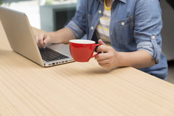 woman holding coffee cup with laptop computer