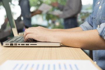 woman typing laptop computer with businessmen discussing with pa