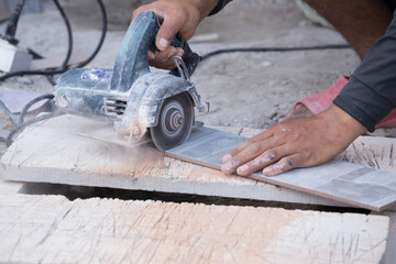 worker cutting a tile using an angle grinder