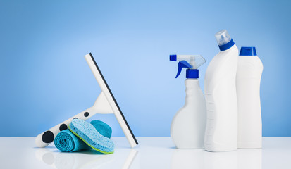 House cleaning products on white table with blue gradient backdrop. Lots of copy space around...