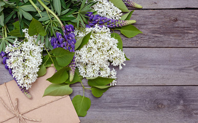 Bouquet of lilac and envelope on wooden background