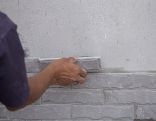 worker install stone wall tile with cement for house