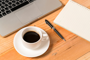 cup of hot coffee beside a laptop close up
