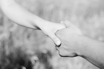 Young couple's hands holding to each other over yellow background outdoors